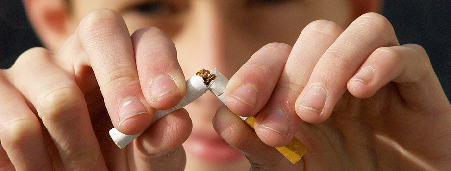 Une personne arrête de fumer par l'hypnose et coupe une cigarette en 2 avec ses doigts